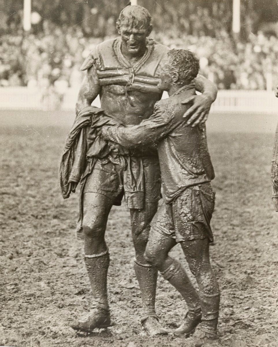 Norm Provan consoling Arthur Summons both covered in mud
